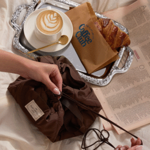 شنطة مكياج محمولة باللون الأسود مفتوحة على شكل مفرش دائري تحتوي على أدوات تجميل وفرش.