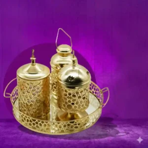 صينية بمجموعة مزخرفة لرمضان، تشمل مبخرة وفانوس وبرطمان تمر، مصنوعة من معدن مطلي بلون دهبي.